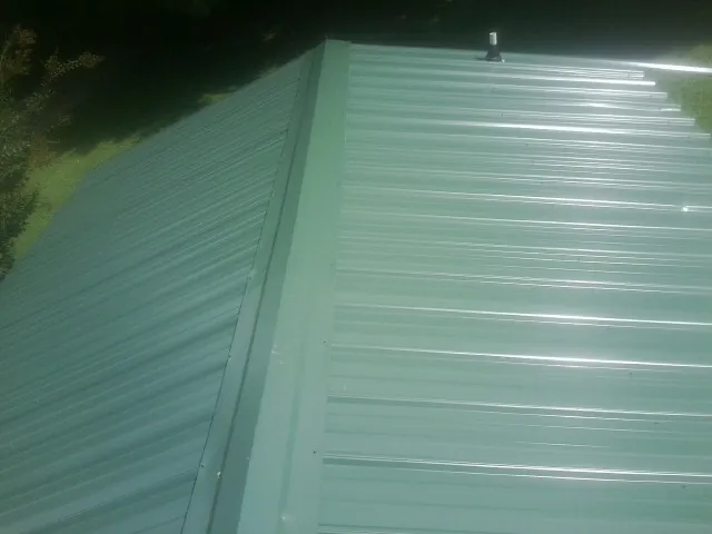 New green metal panels meeting at the ridge of a roof — Flat Roof Repair work by our crew in Two Rivers