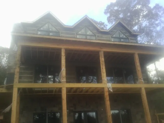 Dormers and porch framing on a large log home under construction — Roof Coating work by our crew in Two Rivers