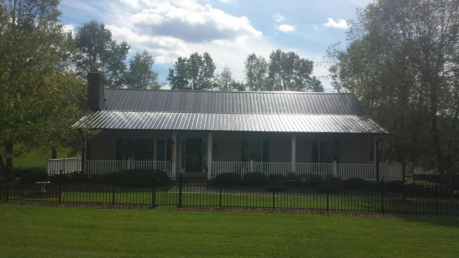 Gray metal roof on a brick ranch with a full width front porch — Gutter Guard Installation work by our crew in Two Rivers