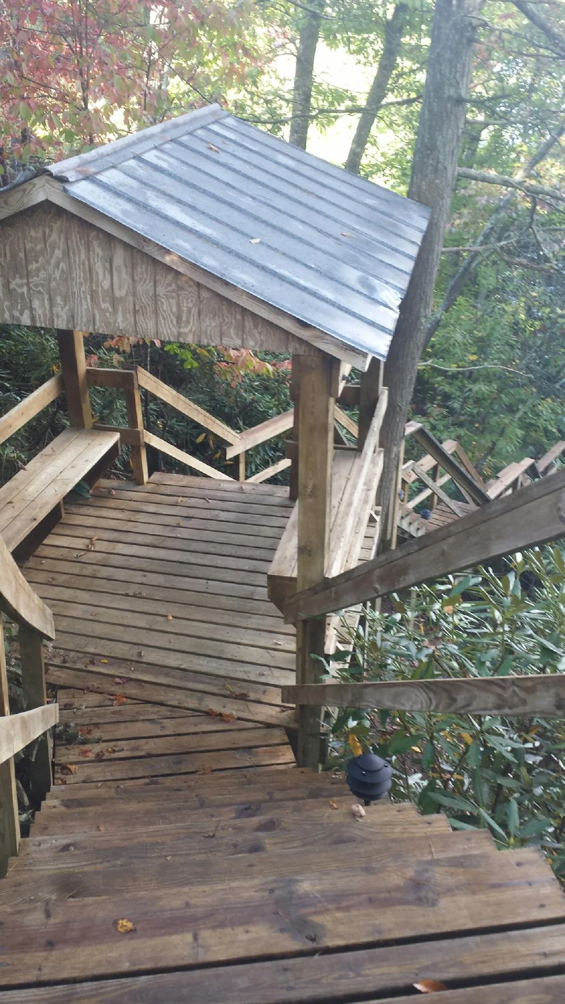 Metal roofed shelter over wooden steps on a wooded walkway — Skylight Repair & Installation work by our crew in Two Rivers