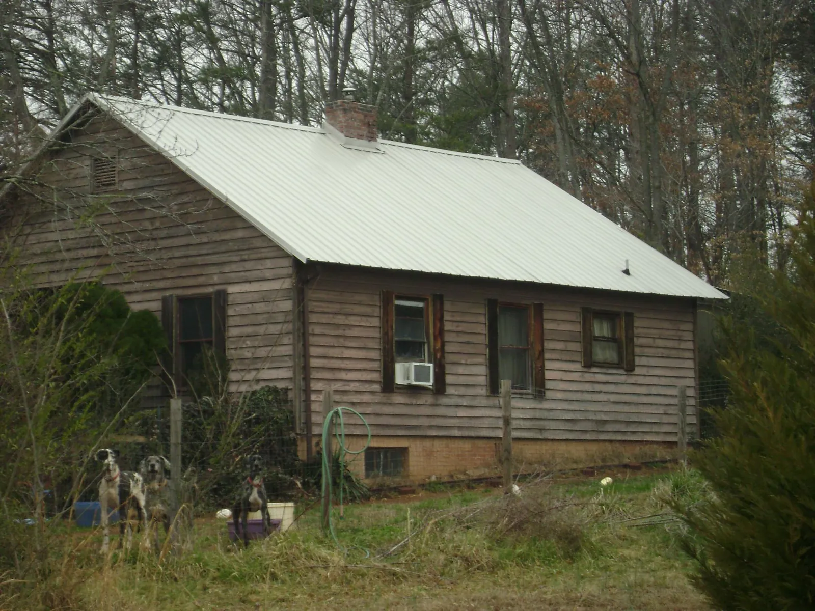White metal roof on an old wood sided farmhouse, from a Metal Roof Installation job in Two Rivers